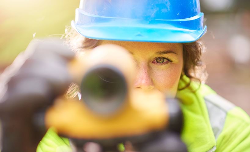 female contsruction worker looking through survey scope